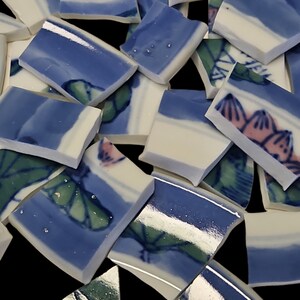 May include: Assortment of blue and white ceramic tile pieces with floral and leaf designs. Some tiles have a silver metallic finish.