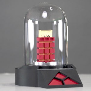 May include: A red and gold electronic component encased in a clear glass dome on a black base with a red triangle logo.