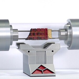May include: A silver and clear tube with a red and brown object inside, mounted on a silver stand with a red base.