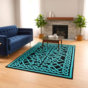 May include: A rectangular black rug with a turquoise Celtic knot design. The rug has a turquoise border and is placed on a hardwood floor in a living room setting. A blue sofa and plants are also visible.