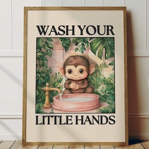 Puede incluir: Lámina artística enmarcada con un mono de dibujos animados lavándose las manos en un lavabo rosa. La imagen está rodeada de follaje verde y el texto "WASH YOUR LITTLE HANDS" se muestra en negro. La obra de arte tiene un estilo vintage y caprichoso.