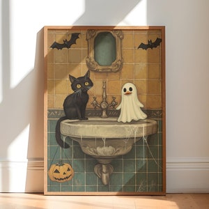 Könnte beinhalten: Eine gerahmte Illustration einer schwarzen Katze und eines weißen Geistes, die in einem Badezimmerwaschbecken stehen. Das Waschbecken ist grün und weiß mit einem Spinnennetz-Design. Eine kleine orangefarbene Kürbislaterne hängt am Wasserhahn.
