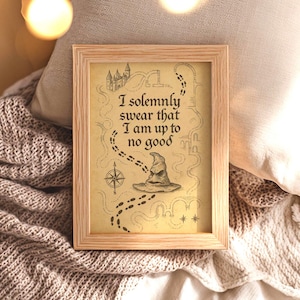 Może przedstawiać: Oprawiony wydruk z jasną drewnianą ramą. Wydruk przedstawia wzór przypominający mapę z zamkiem, śladami stóp i kapeluszem przydziału. Tekst brzmi: „Uroczyście przysięgam, że knuję coś niedobrego”.