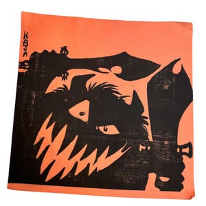 Puede incluir: Cuadrado naranja con una ilustración negra de una cara de monstruo con dientes afilados. La palabra "KAJA" está impresa verticalmente en la esquina superior izquierda. La imagen tiene un aspecto texturizado y vintage.