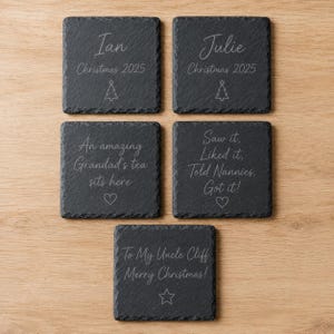 Puede incluir: Cinco posavasos cuadrados de pizarra con bordes naturales y rugosos. Cada posavasos presenta texto y s&iacute;mbolos grabados: Ian Christmas 2025 con un &aacute;rbol, Julie Christmas 2025 con un &aacute;rbol, An amazing Grandad's tea sits here con un coraz&oacute;n, Saw it, Liked it, Told Nannies, Got it! con un coraz&oacute;n, y To My Uncle Cliff Merry Christmas! con una estrella.