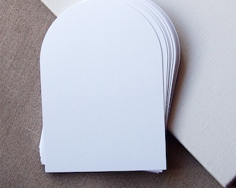 May include: A stack of white, semi-circular cardstock paper, likely for crafting or scrapbooking.