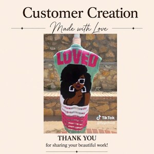 May include: A sleeveless crochet vest featuring a light green base with the word LOVED in large pink letters across the top. Below the text is a graphic of a person with dark hair, white sunglasses, and large hoop earrings, over a white and pink striped pattern.