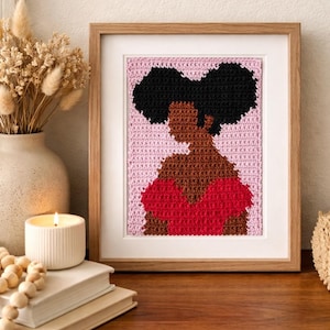 May include: A framed crochet pattern PDF featuring a stylized portrait of a person with dark skin and black hair in two puffs, wearing a red top against a light pink background. The text reads Crochet Pattern PDF, Instant Download, Beginner Friendly.