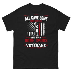 May include: Black t-shirt with a graphic design featuring the American flag, a helmet, and boots. The text reads "ALL GAVE SOME, SOME GAVE ALL, ONE HAD BONE SPURS, VETERANS AGAINST TRUMP."