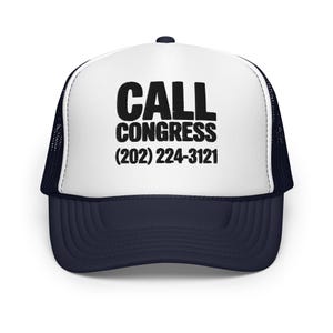 May include: A trucker hat with a white front panel and a navy blue brim and mesh back. The hat features the text "CALL CONGRESS" in bold black letters, along with the phone number (202) 224-3121.