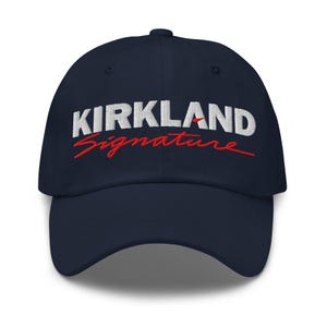 Peut inclure: Casquette de baseball bleu marine avec le texte brodé "KIRKLAND Signature" en blanc et rouge. La casquette a une visière incurvée et un bouton sur le dessus.