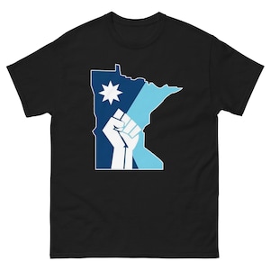 Peut inclure: T-shirt noir avec un motif graphique du contour de l'État du Minnesota en bleu et bleu clair, avec un poing blanc et un motif d'étoile. Le t-shirt est fait d'une matière douce et confortable.
