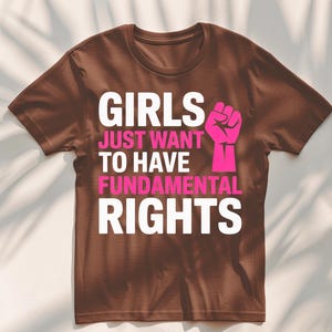 May include: Brown t-shirt with white text that reads "Girls Just Want To Have Fundamental Rights" and a pink fist graphic.