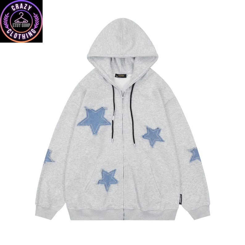 May include: A light gray zip-up hoodie with a hood and blue star patches. The hoodie has a black zipper and a small logo on the sleeve. The Crazy Clothing Etsy Shop logo is in the upper left corner.