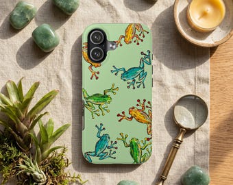 Puede incluir: Funda de teléfono verde claro con un patrón de ranas coloridas. Las ranas están representadas en azul, verde y amarillo con detalles rojos. La escena incluye piedras verdes, una lupa y una pequeña planta.