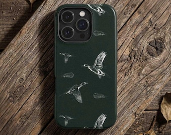 Puede incluir: Funda de teléfono verde oscuro con una ilustración blanca de patos volando. La funda tiene un acabado mate y un diseño protector. La funda se muestra sobre una superficie de madera.