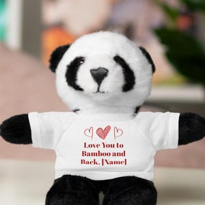 May include: A white and black panda bear plush toy wearing a white t-shirt with red hearts and the text "Love You to Bamboo and Back, [Name]"