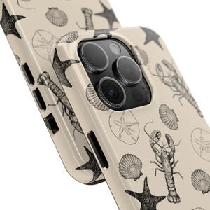 May include: A beige phone case featuring a repeating pattern of black starfish, seashells, sand dollars, and a lobster illustration. The case is designed to fit a smartphone, with cutouts for the camera and buttons.