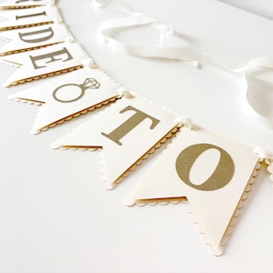May include: A white ceramic mug with a black handle and the text "But first, coffee" in a handwritten style. The mug is on a white surface. The mug is 4 inches tall.
