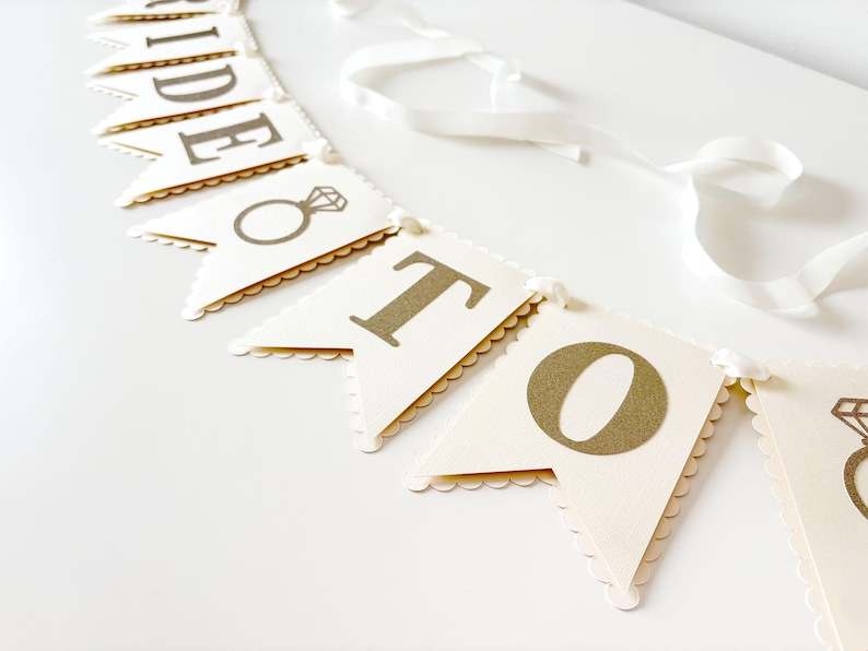 May include: A white ceramic mug with a black handle and the text "But first, coffee" in a handwritten style. The mug is on a white surface. The mug is 4 inches tall.