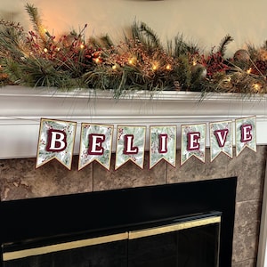 May include: A festive banner with a green and gold background and red lettering that reads "BELIEVE". The banner is hung above a fireplace with a garland of pine branches and red berries.