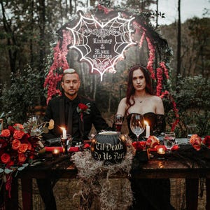 Peut inclure: Une table de r&eacute;ception de mariage avec une citrouille noire sur laquelle est inscrit "Til Death Do Us Part" et une enseigne au n&eacute;on en forme de c&oelig;ur avec une toile d'araign&eacute;e qui dit "Lindsey & Ryan 03.12.2025".