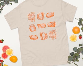 Può includere: Una t-shirt beige con una stampa grafica arancione di un gatto in varie posizioni. Il gatto è raffigurato in uno stile pixelato, con un effetto glitch.