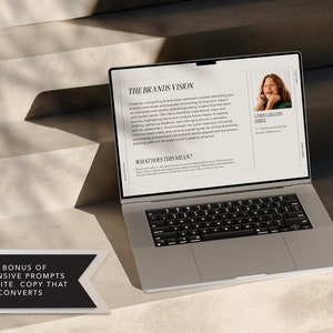 May include: A laptop computer open to a page with the title "The Brands Vision" and a section titled "What Does This Mean?" The page also includes a photo of a young woman smiling. The text on the page discusses creating a compelling brand vision statement.