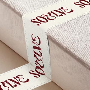 Może przedstawiać: Dwa białe pudełka z czerwonym, kursywnym tekstem. Tekst na górnym pudełku brzmi "SOUVENIR", a tekst na dolnym pudełku brzmi "SOUVENIR".