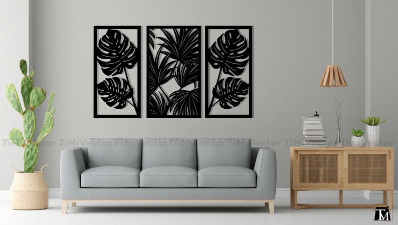 May include: Three black metal wall decor panels with cut-out tropical leaf designs. The panels are arranged in a row on a white wall above a gray sofa.