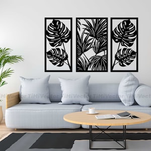 May include: Three black metal wall decor panels with cut-out tropical leaf designs. The panels are arranged horizontally on a white wall above a gray sofa.
