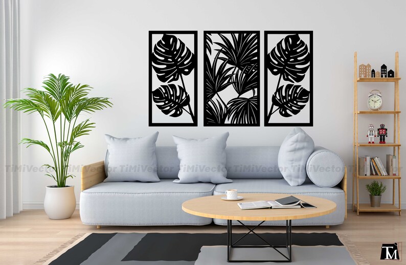 May include: Three black metal wall decor panels with cut-out tropical leaf designs. The panels are arranged horizontally on a white wall above a gray sofa.