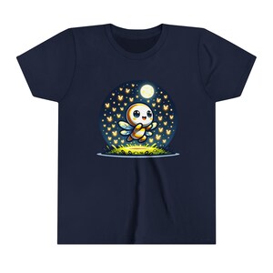Puede incluir: Una camiseta azul marino con una ilustración de dibujos animados de una luciérnaga amarilla y blanca volando en un círculo de luciérnagas brillantes bajo una luna creciente.