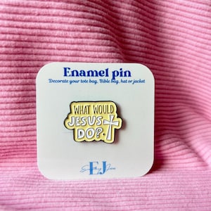 Puede incluir: Pin de esmalte amarillo y negro con el texto "WHAT WOULD JESUS DO?" sobre una tarjeta blanca. La tarjeta también presenta las palabras "Enamel pin" y "Decorate your tote bag, Bible bag, hat or jacket".