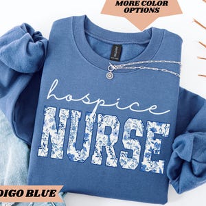 May include: Indigo blue sweatshirt with a floral design and the text "hospice nurse" in white.
