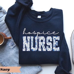 May include: Navy blue sweatshirt with white floral print and the text "hospice nurse" in white.