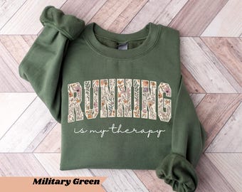 May include: Military green sweatshirt with the text "RUNNING is my therapy" in a floral design. The sweatshirt is a crew neck style with long sleeves. The text "Military Green" is at the bottom of the image.