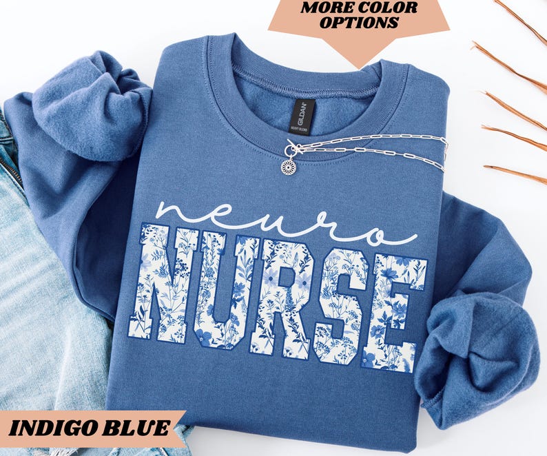 Puede incluir: Sudadera azul &iacute;ndigo con un dise&ntilde;o floral y el texto "neuro nurse" en blanco.