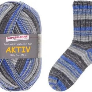 May include: A ball of Aktiv yarn in blue, gray, and black next to a matching sock. The yarn label reads "SUPERGARNE AKTIV" and includes the weight and length. The sock has a ribbed cuff and a striped pattern.
