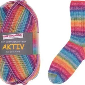 May include: A ball of Aktiv Supergarne yarn and a matching rainbow-coloured sock. The yarn is multi-coloured with shades of pink, purple, orange, yellow, blue, and green. The sock has a ribbed cuff and a striped pattern.