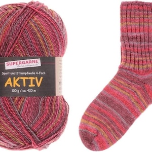 May include: A ball of Aktiv yarn in shades of red, pink, and yellow next to a matching sock. The yarn label reads "SUPERGARNE" and "AKTIV 100 g / ca. 420 m". The sock has horizontal stripes of the same colors.