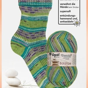 May include: A green, blue, and purple striped sock next to a matching ball of Opal Beauty Balance yarn. The yarn label reads "Balance" and "100g". The image also includes text that reads "Heilpflanze des Jahres 2019 (AT)".
