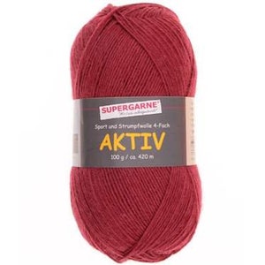 May include: A ball of red yarn with a label that reads "SUPERGARNE AKTIV". The label also indicates the yarn is sport and sock wool, 100 g / ca. 420 m. The yarn is a deep, rich red color.