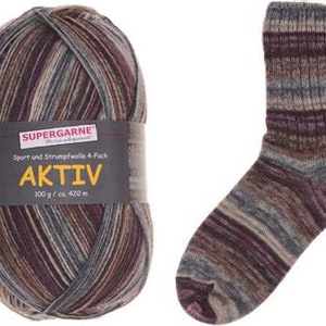 May include: A ball of Aktiv yarn with a matching sock. The yarn is multi-colored with shades of brown, gray, and purple. The sock has a ribbed cuff and is made from the same yarn. The label reads "SUPERGARNE AKTIV".