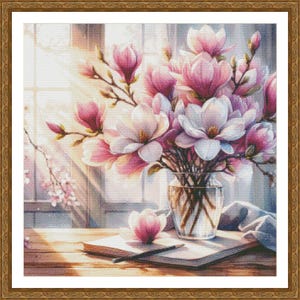 Peut inclure: Un bouquet de fleurs de magnolia roses et blanches dans un vase en verre transparent sur une table en bois avec un carnet et un crayon. Les fleurs sont &eacute;clair&eacute;es par la lumi&egrave;re du soleil qui traverse une fen&ecirc;tre.