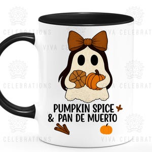 May include: White ceramic mug with a black handle and rim, featuring a ghost illustration with a brown bow, holding a pumpkin and a pan de muerto. The text "PUMPKIN SPICE & PAN DE MUERTO" is printed below the ghost, with cinnamon sticks and a small pumpkin.
