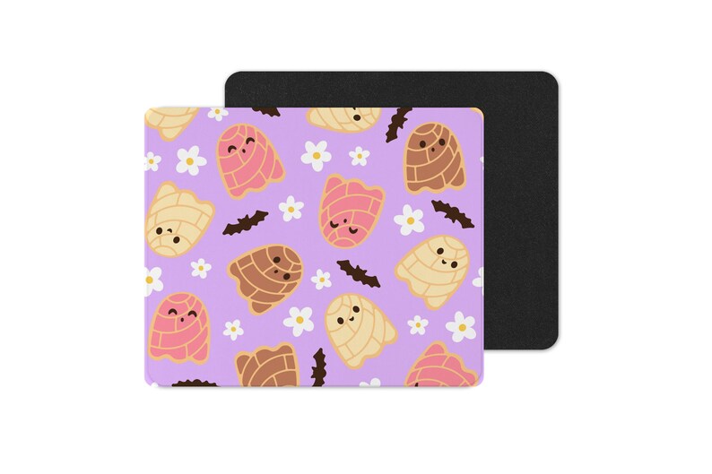 Puede incluir: Una alfombrilla de rat&oacute;n cuadrada con un fondo morado claro que presenta un patr&oacute;n repetido de pasteles de concha sonrientes en colores rosa, marr&oacute;n y crema, junto con flores blancas y murci&eacute;lagos negros. Una almohadilla rectangular negra est&aacute; detr&aacute;s.