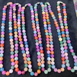 May include: A multi-strand necklace made of colorful round beads. The beads are translucent and have a variety of colors, including pink, blue, green, and yellow.