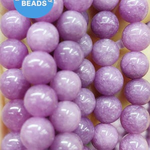 May include: Strands of round, glossy, lavender-colored beads. The beads are uniform in size and shape, with a smooth surface. The image includes a blue circle with the text "WK DIY Jewelry BEADS".
