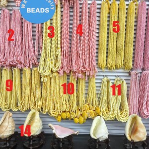 May include: A display of beaded necklaces in various colors, including yellow, pink, and white. Several seashells are also displayed. The necklaces are numbered for easy reference. The word "BEADS" is in a blue circle.